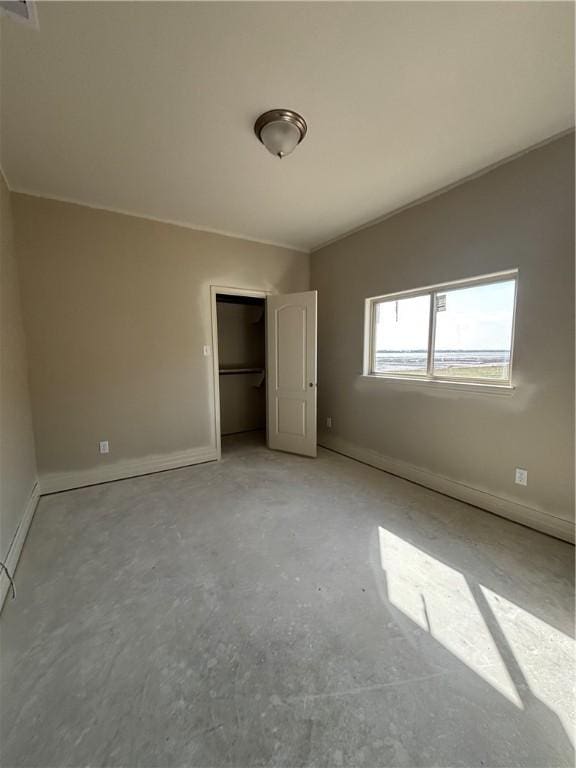 unfurnished bedroom featuring vaulted ceiling, a closet, unfinished concrete flooring, and baseboards