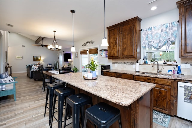 kitchen with white dishwasher, pendant lighting, sink, light hardwood / wood-style floors, and a center island