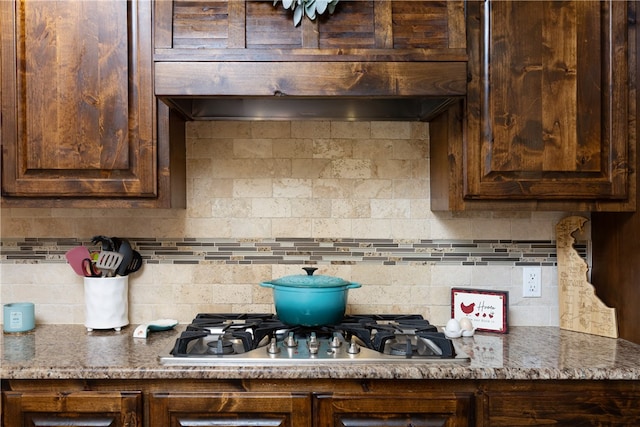 kitchen featuring tasteful backsplash, stainless steel gas stovetop, dark brown cabinetry, and stone countertops