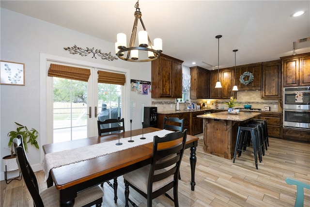 dining room with an inviting chandelier, french doors, and light hardwood / wood-style floors