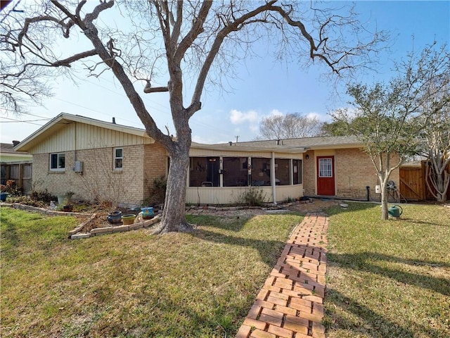 rear view of property featuring a yard and a sunroom