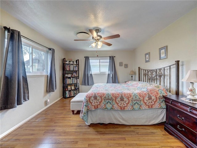 bedroom featuring multiple windows, light hardwood / wood-style floors, and ceiling fan