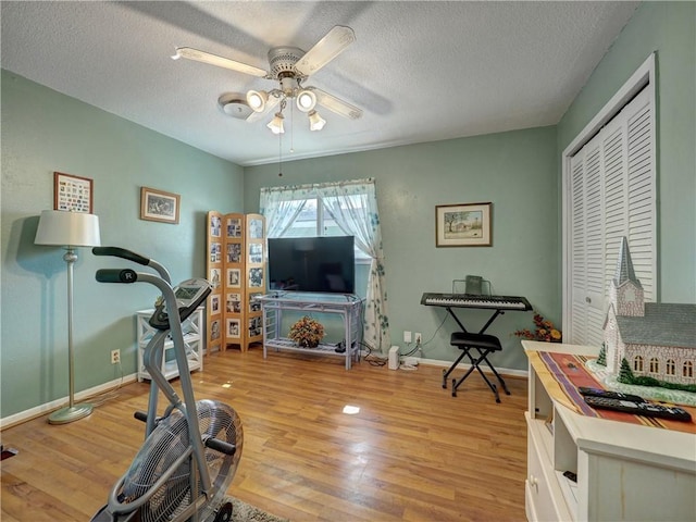 workout room with ceiling fan, a textured ceiling, and light hardwood / wood-style floors