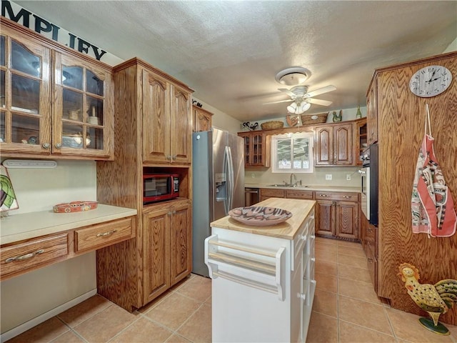 kitchen featuring butcher block counters, light tile patterned floors, stainless steel appliances, and ceiling fan