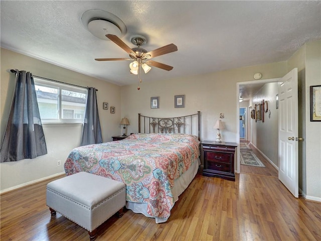 bedroom with ceiling fan, a textured ceiling, and light wood-type flooring