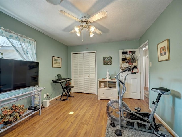 workout area featuring a textured ceiling, light hardwood / wood-style flooring, and ceiling fan