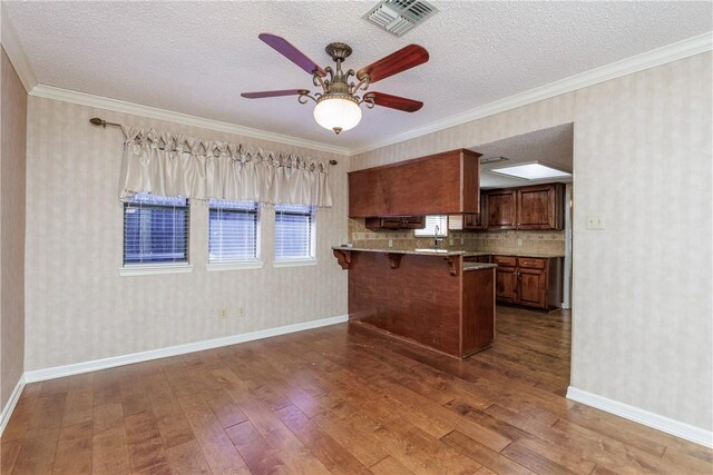 4119 Crenshaw Dr, Corpus Christi, TX 78413 - kitchen featuring dark wood-type flooring, a kitchen bar, a peninsula, a textured ceiling, and baseboards