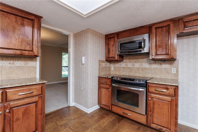 4119 Crenshaw Dr, Corpus Christi, TX 78413 - kitchen with appliances with stainless steel finishes, brown cabinetry, and a textured ceiling