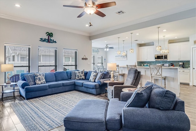 living room featuring light hardwood / wood-style floors, ceiling fan, and crown molding