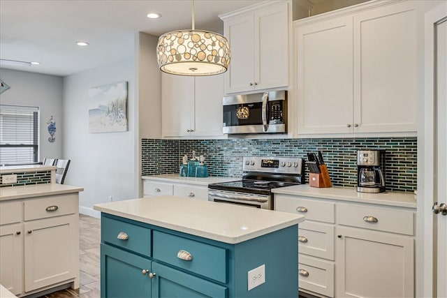 kitchen with stainless steel appliances, white cabinetry, blue cabinetry, a center island, and pendant lighting