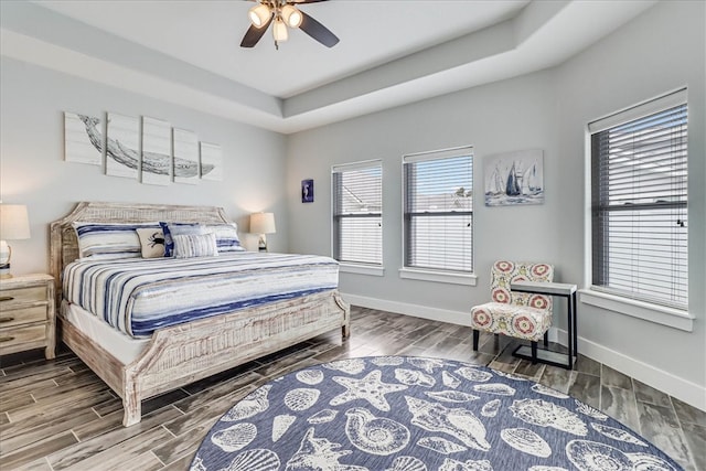 bedroom featuring hardwood / wood-style flooring, ceiling fan, and a raised ceiling