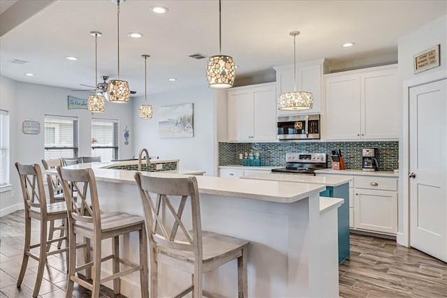 kitchen with white cabinets, stainless steel appliances, and an island with sink