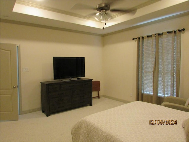 carpeted bedroom with a tray ceiling, ceiling fan, and ornamental molding