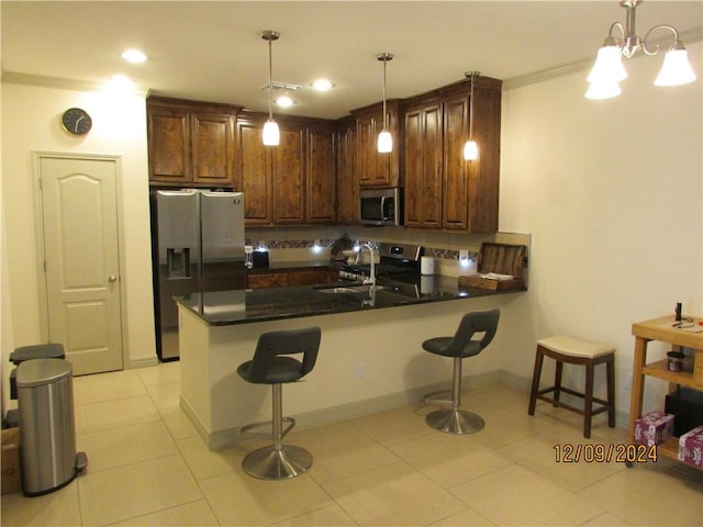 kitchen featuring a kitchen bar, kitchen peninsula, pendant lighting, and appliances with stainless steel finishes