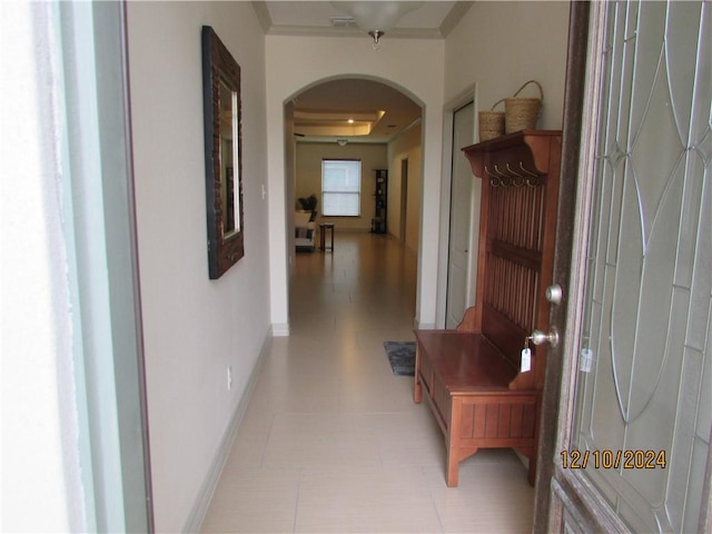 hallway with a tray ceiling and ornamental molding