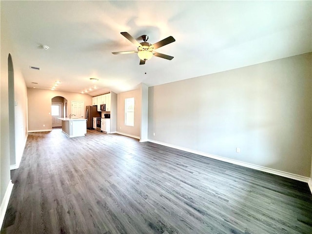 1108 N Staples St, Corpus Christi, TX 78401 - unfurnished living room with arched walkways, baseboards, dark wood-style floors, and ceiling fan
