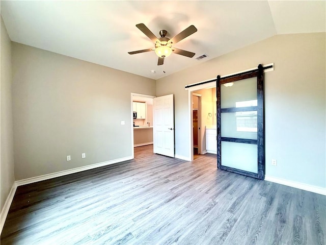 1108 N Staples St, Corpus Christi, TX 78401 - unfurnished bedroom featuring a barn door, wood finished floors, baseboards, and a ceiling fan