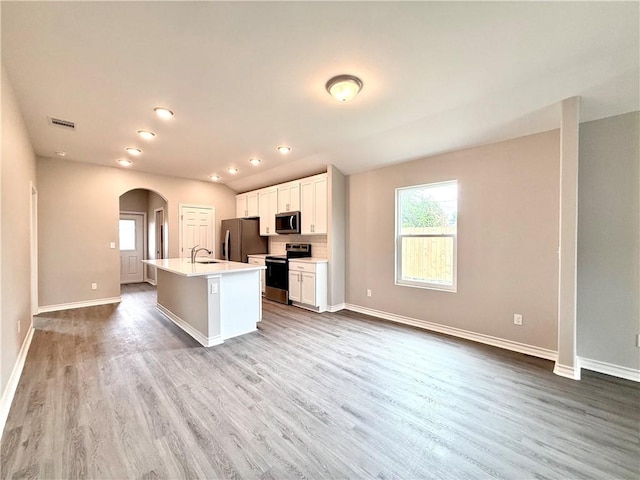 1108 N Staples St, Corpus Christi, TX 78401 - kitchen featuring stainless steel appliances, arched walkways, a center island with sink, wood finished floors, and white cabinets