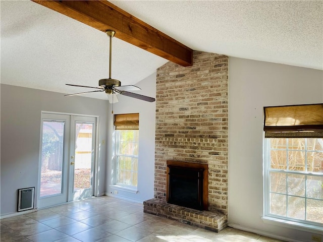 unfurnished living room with a textured ceiling, ceiling fan, light tile patterned floors, lofted ceiling with beams, and a fireplace