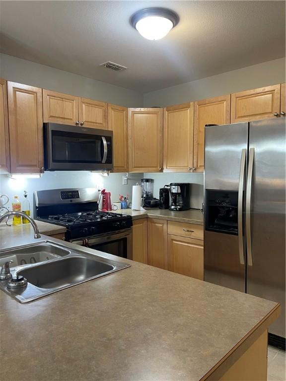 kitchen featuring stainless steel appliances, light brown cabinets, and sink