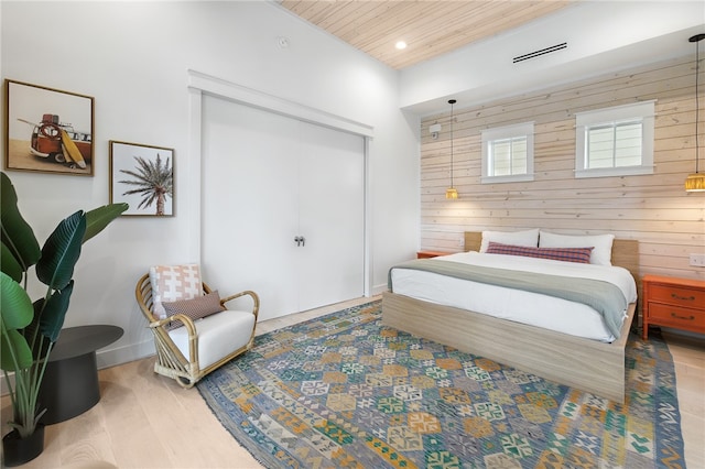 bedroom with a closet, wood-type flooring, wooden ceiling, and wood walls