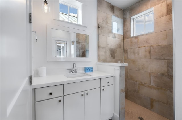 bathroom with a wealth of natural light, vanity, and a tile shower