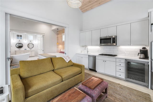 living room with wine cooler, light wood-type flooring, high vaulted ceiling, wood ceiling, and sink