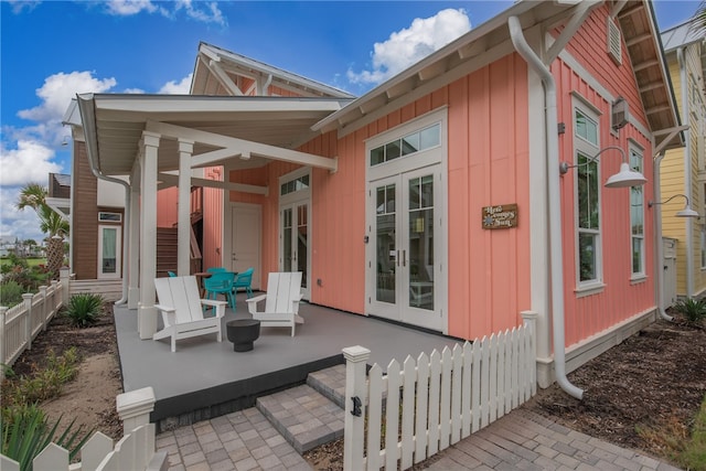 rear view of property featuring covered porch and french doors