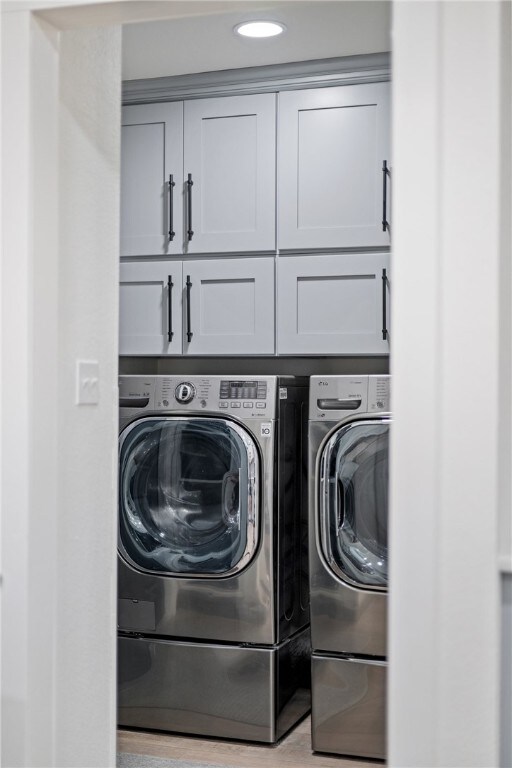 laundry room featuring cabinet space, light wood-style flooring, and independent washer and dryer