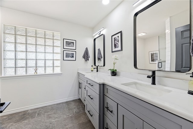 bathroom featuring a sink, baseboards, and double vanity