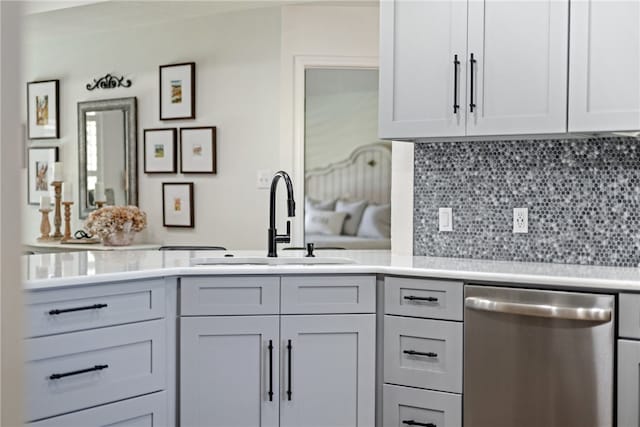 kitchen featuring light countertops, dishwasher, backsplash, and a sink