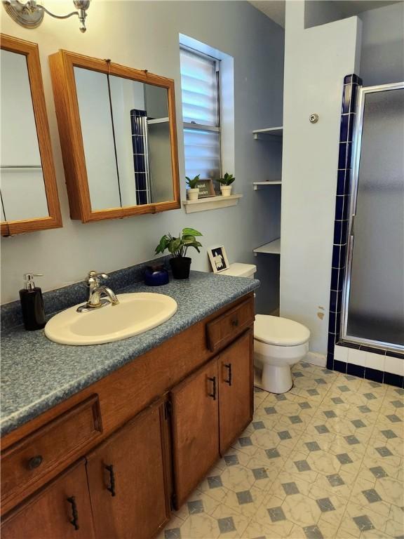 bathroom featuring an enclosed shower, vanity, and toilet