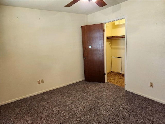 unfurnished bedroom with dark colored carpet, a spacious closet, ceiling fan, and a closet