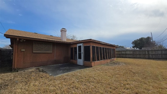 rear view of house featuring a sunroom, a patio area, and a lawn