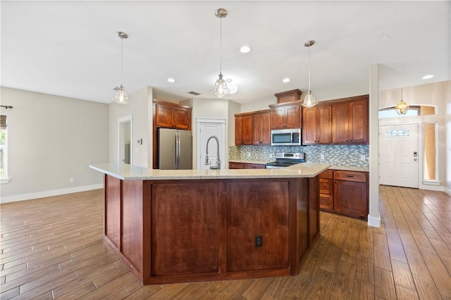 2342 Vaughan Dr, Corpus Christi, TX 78414 - kitchen with appliances with stainless steel finishes, wood finished floors, backsplash, a spacious island, and hanging light fixtures