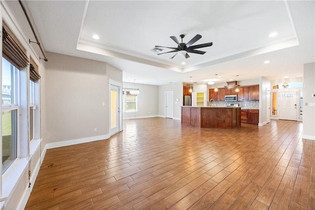 2342 Vaughan Dr, Corpus Christi, TX 78414 - unfurnished living room with a tray ceiling, ceiling fan, recessed lighting, wood finished floors, and a chandelier