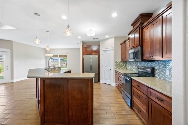 2342 Vaughan Dr, Corpus Christi, TX 78414 - kitchen featuring stainless steel appliances, tasteful backsplash, a center island with sink, light wood-type flooring, and hanging light fixtures