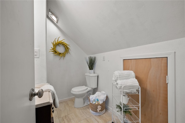 bathroom featuring toilet, vanity, and vaulted ceiling