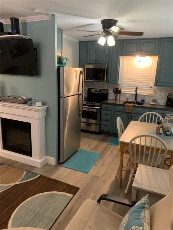 kitchen with crown molding, a sink, a ceiling fan, appliances with stainless steel finishes, and backsplash