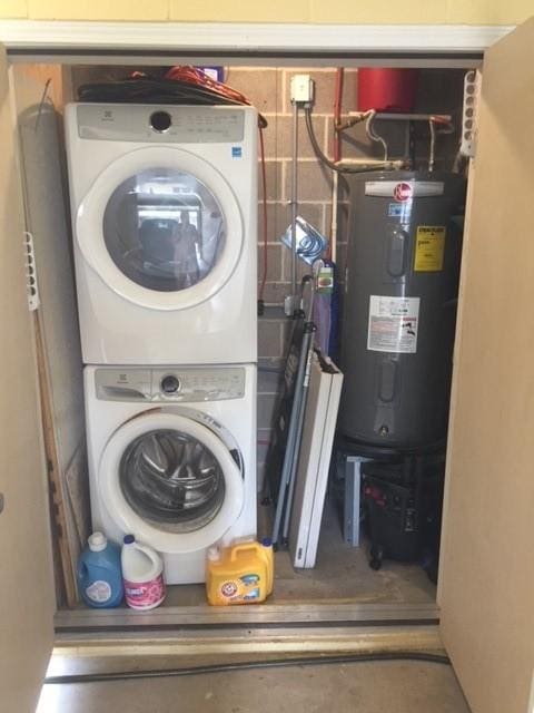 clothes washing area with laundry area, water heater, and stacked washer / drying machine