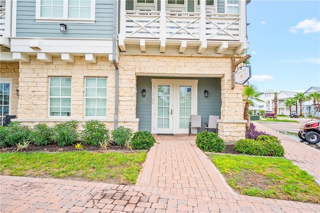 view of exterior entry featuring french doors and a balcony