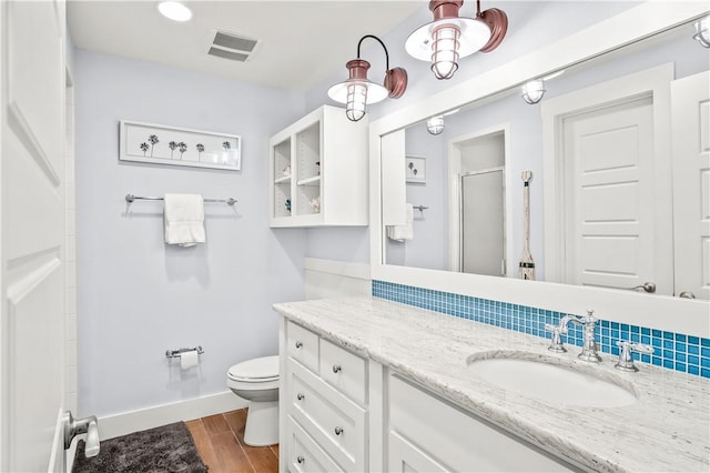 bathroom featuring vanity, hardwood / wood-style flooring, a shower with shower door, and toilet