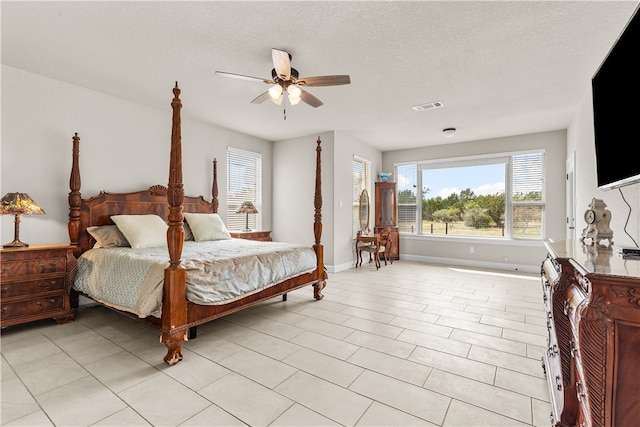 bedroom featuring a textured ceiling, light tile patterned floors, and ceiling fan