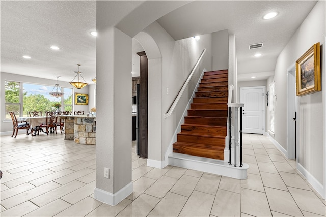 stairway featuring a textured ceiling and tile patterned floors