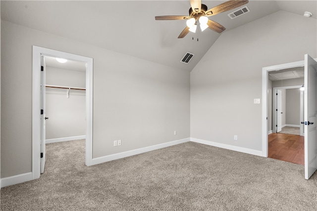 unfurnished bedroom with carpet flooring, ceiling fan, vaulted ceiling, and a walk in closet