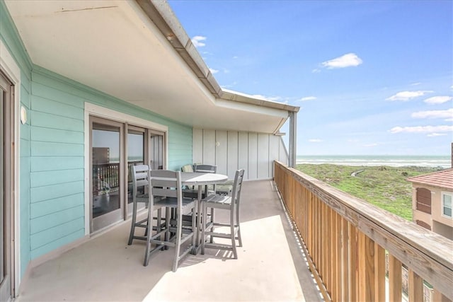 balcony with outdoor dining area and a water view