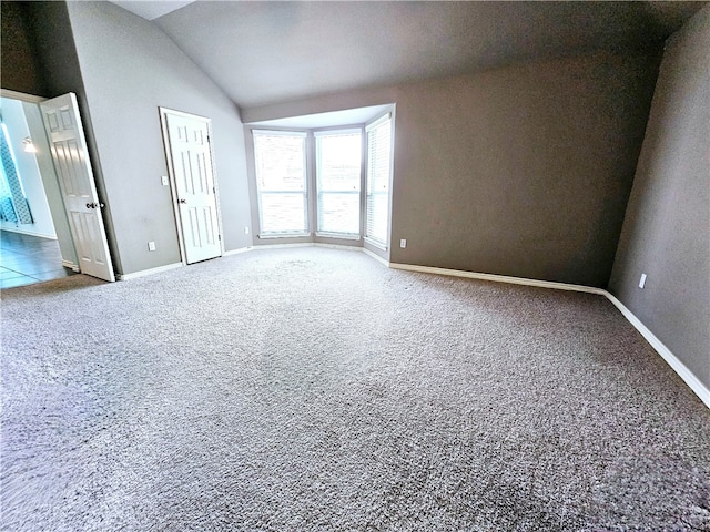 carpeted spare room featuring vaulted ceiling