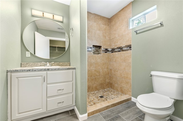 bathroom featuring tiled shower, toilet, and vanity