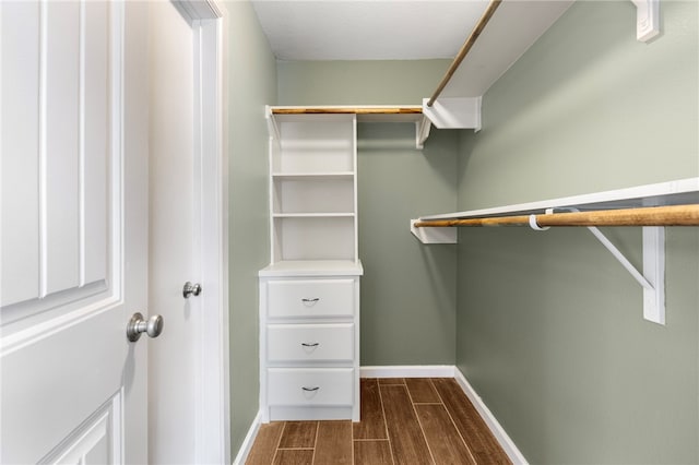 walk in closet with dark wood-type flooring