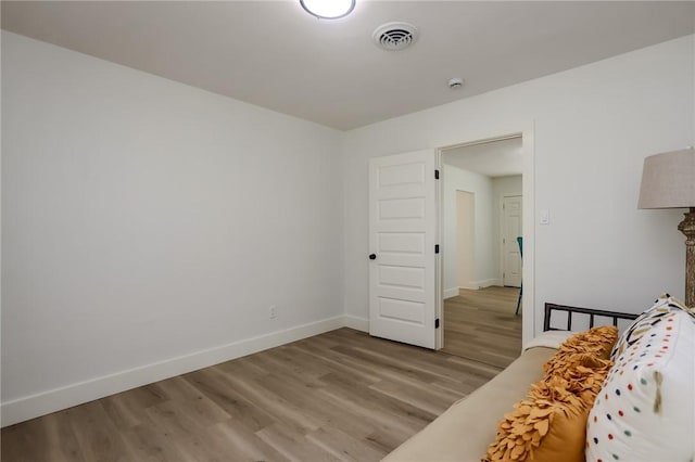 bedroom featuring baseboards, wood finished floors, and visible vents